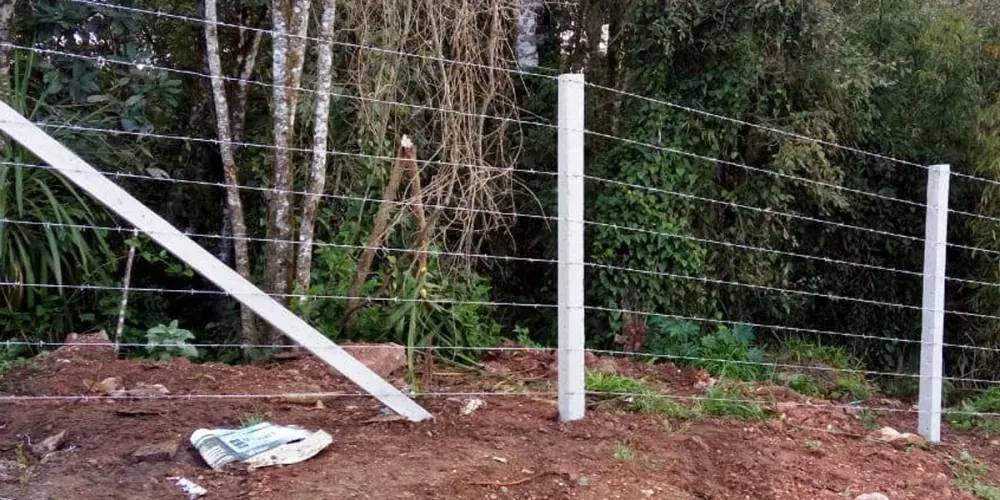 Cercamento com arame farpado e mourões de concreto
