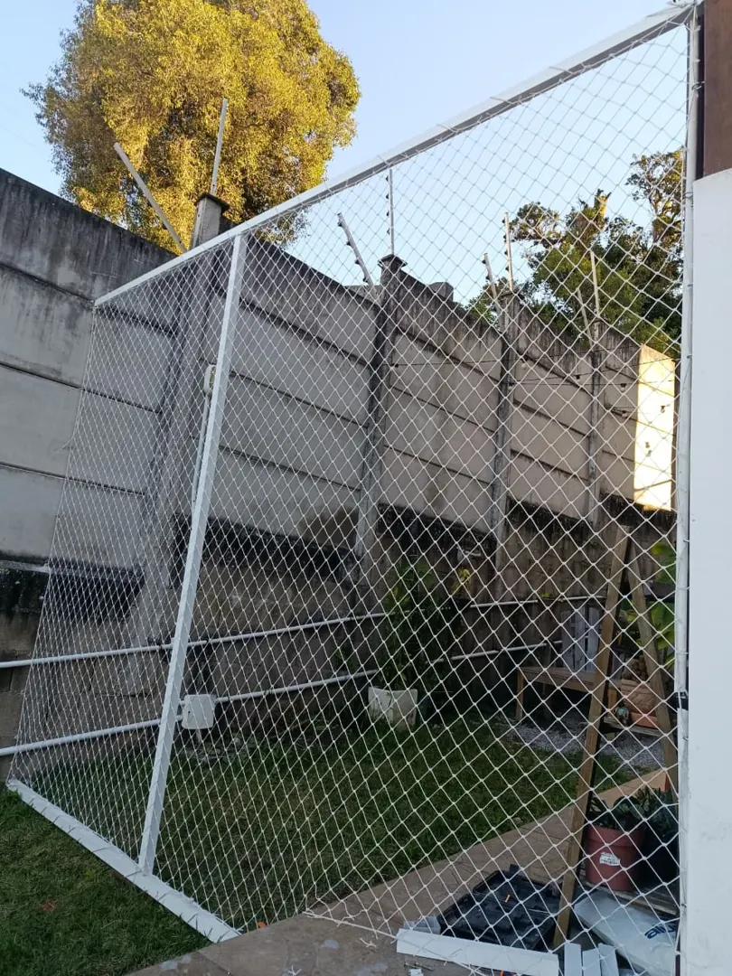 Fechamento residencial com rede branca e estrutura metálica